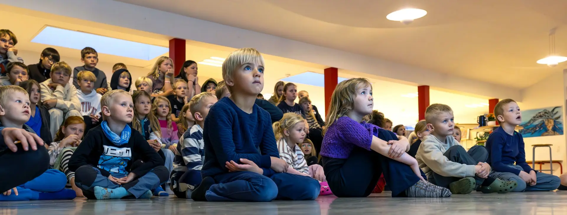 Hele skolen sidder samlet på gulvet til morgensamling
