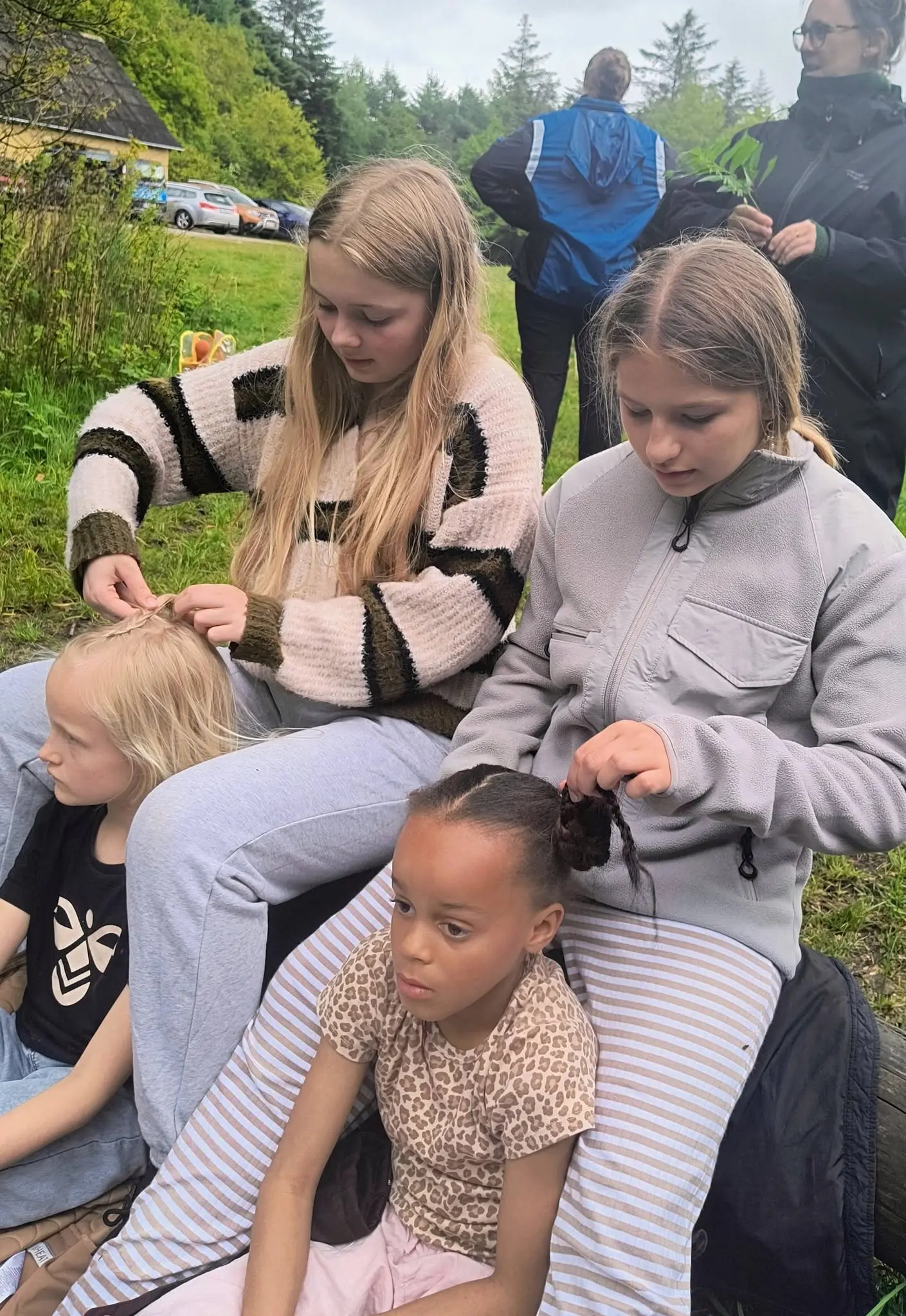 To store piger fletter hår på en yngre pige