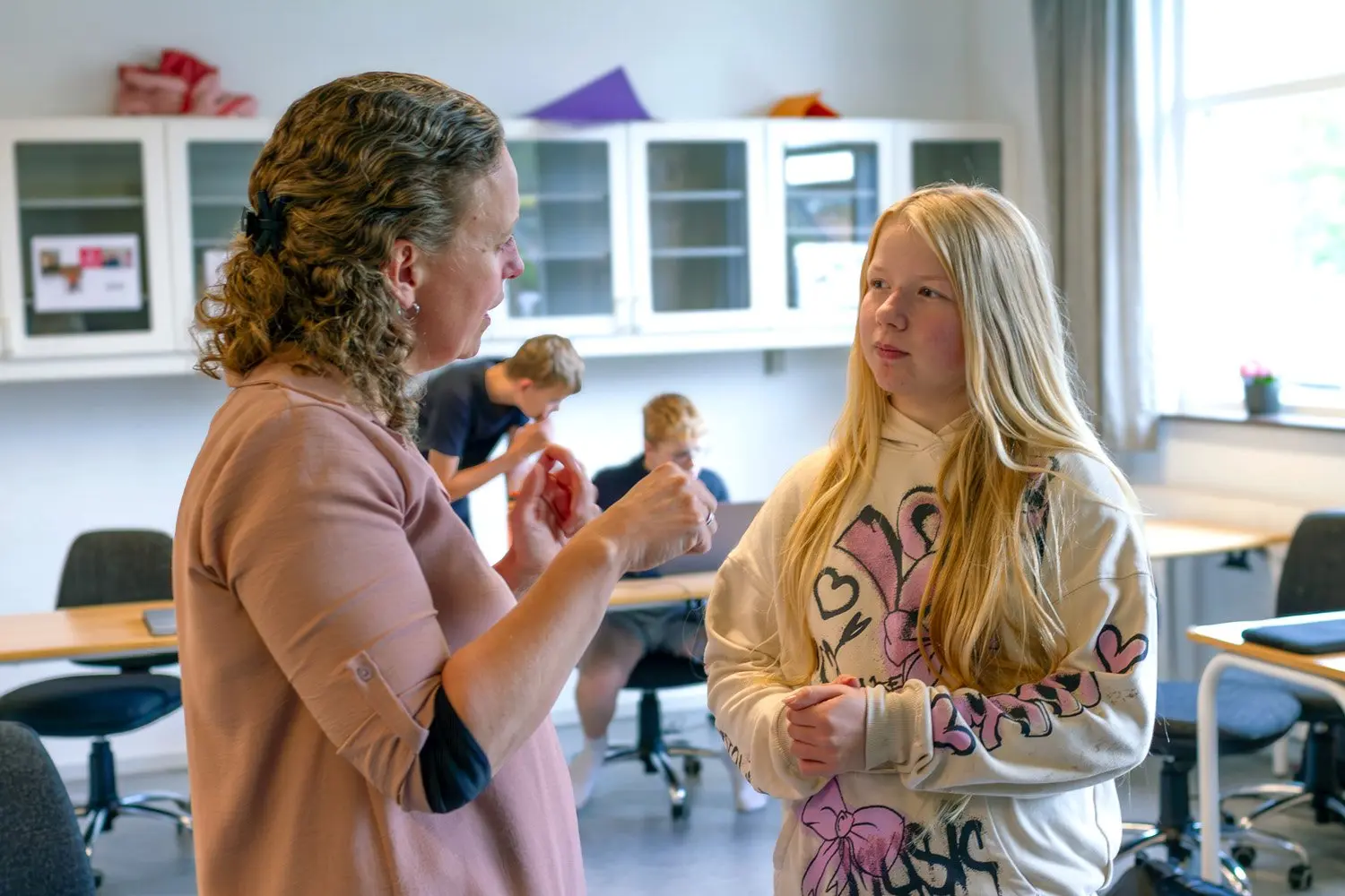 Lærer taler med en elev i klasselokalet