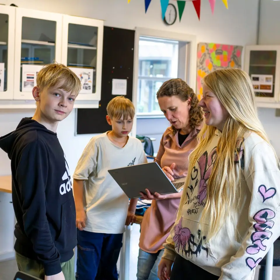 Elever står samlet om en tablet i klasselokalet